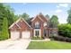 Charming brick home featuring a two-car garage, manicured lawn, and welcoming front entry at 417 Rhodes House Dr, Suwanee, GA 30024
