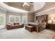 Large main bedroom with a seating area, tray ceilings, and an ensuite bathroom at 417 Rhodes House Dr, Suwanee, GA 30024