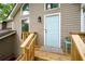 Close-up of the charming light blue front door with white trim, complemented by a wooden deck and a small table at 2445 Deerfield Nw Dr, Kennesaw, GA 30144