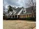 Charming brick home with dormer windows, yellow shutters, covered porch, and mature landscaping at 325 Northmill Pkwy, Stockbridge, GA 30281
