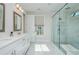 Bright bathroom featuring double vanity with white marble countertop, brushed gold fixtures, and glass enclosed shower at 750 Tannery Cmn, Alpharetta, GA 30009