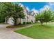 A view of the home from the lawn showing stone accents, lush trees, and a front-facing garage at 2552 Berwick Walk, Snellville, GA 30078