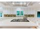 Detailed close up of kitchen island with gas cooktop, white cabinets, and tiled backsplash at 2552 Berwick Walk, Snellville, GA 30078