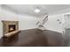 Large living room with a stone fireplace, hardwood floors, bright lighting, and access to a staircase at 3700 Terrasol Sw Trl, Lilburn, GA 30047