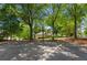 Community basketball court surrounded by mature trees on a sunny day with a home in the background at 1667 Willow Way, Woodstock, GA 30188