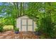 Outdoor storage shed surrounded by lush greenery and landscaping at 1667 Willow Way, Woodstock, GA 30188