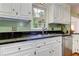 Close-up of kitchen sink, white cabinets, black countertops, and hardwood floors at 4546 Windsor Oaks Ct, Marietta, GA 30066
