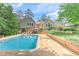 Inviting backyard with pool, wooden retaining wall, lush lawn, and multi-level deck accessible from the house at 4546 Windsor Oaks Ct, Marietta, GA 30066