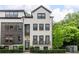 Beautiful three-story townhome featuring a painted brick exterior, dark window trim, and manicured landscaping at 4538 Collins Ave, Sandy Springs, GA 30342