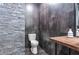A contemporary bathroom showcases textured stone, a modern toilet, and floating shelves for a minimalist aesthetic at 6355 Westfallen Overlook, Cumming, GA 30040