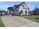 Wide concrete driveway leading to a three-car garage, surrounded by a lush, green lawn at 6355 Westfallen Overlook, Cumming, GA 30040