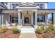 Inviting front porch with seating areas, columns, and decorative lighting fixtures creating a warm entry at 6355 Westfallen Overlook, Cumming, GA 30040
