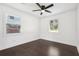 Light-filled bedroom with two windows, fan, and sleek dark hardwood flooring at 7540 Conyers St, Lithonia, GA 30058