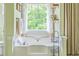Bright bathroom showcasing a soaking tub, light green walls, natural light from a window, and decorative shelves at 102 Woodsfield Ln, Hiram, GA 30141