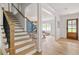 Bright foyer with hardwood floors, featuring a staircase with wooden banister and black iron balusters, and an open living area at 1155 Peachtree Battle Nw Ave, Atlanta, GA 30327