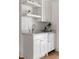Wet bar featuring white cabinetry, floating shelves, mini fridge, a sink and laminate wood flooring at 1155 Peachtree Battle Nw Ave, Atlanta, GA 30327