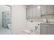 Bright laundry room features gray cabinets, marbled floors, and adjacent bathroom with glass shower and white soaking tub at 2346 East Maddox Rd, Buford, GA 30518