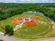 Aerial view of baseball and softball fields surrounded by greenery, offering ample space for sports and recreation at 7455 Cordery Rd, Cumming, GA 30040