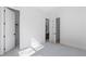 Bright bedroom with neutral carpet and white walls with three visible doorways to a bathroom and closets at 298 Tillman Pass, Woodstock, GA 30188