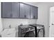 Well-equipped laundry room with modern washer and dryer, ample cabinet storage, and a utility sink at 298 Tillman Pass, Woodstock, GA 30188