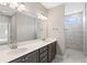 Spacious bathroom featuring double sinks, light gray walls, decorative mirrors, and a tiled shower at 313 Sassafras Way, Holly Springs, GA 30115