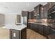 Modern kitchen featuring dark wood cabinets, stainless steel appliances, a center island, and a tile backsplash at 313 Sassafras Way, Holly Springs, GA 30115