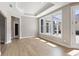 Sun-filled living room featuring hardwood floors, tray ceiling, and large windows at 313 Sassafras Way, Holly Springs, GA 30115
