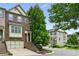 Charming brick townhome featuring a two-car garage, lush landscaping, and a welcoming entrance staircase at 2143 Yancey Ne Ln, Atlanta, GA 30319