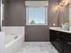 Bathroom featuring a soaking tub, dark wood vanity, and marble floors, illuminated by natural light at 1580 Johnson Nw Rd, Atlanta, GA 30318