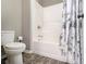 Bright bathroom showing toilet, shower and tub combination with neutral walls and stone-look tile floor at 1580 Johnson Nw Rd, Atlanta, GA 30318