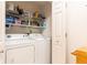 Bright laundry room features white washer and dryer plus shelving at 211 Colonial Homes Nw Dr # 2203, Atlanta, GA 30309