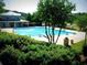 Community swimming pool surrounded by green bushes, lawn chairs, and a two-story building at 2075 Six Branches, Roswell, GA 30076