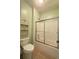 Clean bathroom featuring a shower-tub combo with sliding glass doors and a decorative shelving unit at 3400 Suwanee Creek Rd, Suwanee, GA 30024
