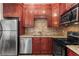 Updated kitchen showcasing cherry cabinets, stainless steel appliances, and beautiful backsplash at 1421 Peachtree Ne St # 211, Atlanta, GA 30309
