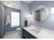 Charming blue bathroom with a large round mirror, modern fixtures, and a shower-curtained bath, offering a cozy design at 2890 Howell Mill Rd, Atlanta, GA 30327