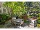 Outdoor dining area with stone patio, lush landscaping, and mature trees at 2890 Howell Mill Rd, Atlanta, GA 30327