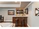 Elegant bar area with custom cabinetry, stone counters, stylish lighting, and seating for two at 690 Sienna Dr, Cumming, GA 30040