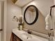 Bathroom featuring a large, round mirror, white marble countertops, and dark cabinets at 1595 Northcliff Trce, Roswell, GA 30076
