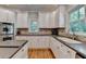 A kitchen features white cabinets, stainless steel appliances, tile backsplash, and hardwood floors at 1595 Northcliff Trce, Roswell, GA 30076