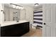 A bathroom with black cabinetry, modern fixtures, wood look tile floor, and a shower featuring a purple and white shower curtain at 1721 Mulberry Lake Dr, Dacula, GA 30019