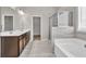 Bright bathroom featuring a double sink vanity, a glass enclosed shower, and a soaking tub with tile surround at 3477 Ivy Birch Way, Buford, GA 30519