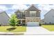 Inviting two-story home featuring stone accents, a manicured lawn, and a two-car garage under a partly cloudy sky at 3477 Ivy Birch Way, Buford, GA 30519