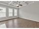 Bright living room with tray ceiling, ceiling fan, large windows with blinds, and hardwood floors at 3477 Ivy Birch Way, Buford, GA 30519