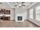 Inviting living room with a fireplace, tray ceiling, hardwood floors, and large windows for ample sunlight at 3477 Ivy Birch Way, Buford, GA 30519