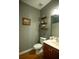Well lit bathroom with vanity, wall shelves and standard toilet at 4271 Haywater Cv, Buford, GA 30519