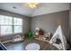 Neutral bedroom featuring a play area, wooden floors and a large window at 4271 Haywater Cv, Buford, GA 30519