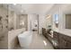 Luxurious main bathroom showcasing dual vanities, a modern soaking tub, and a frameless walk-in shower at 5247 Flannery Chase Sw, Powder Springs, GA 30127