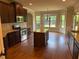 Open kitchen featuring dark wood cabinets, granite countertops, and a central island with hardwood floors at 1307 Clarecastle Ln, Buford, GA 30519