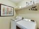 A well-organized laundry room featuring modern washer and dryer units and storage shelves at 352 Hickory Haven Ter, Suwanee, GA 30024