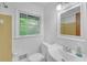 Bathroom with a white toilet, sink, and window with an updated mirror cabinet at 4856 Rock Haven Dr, Lilburn, GA 30047